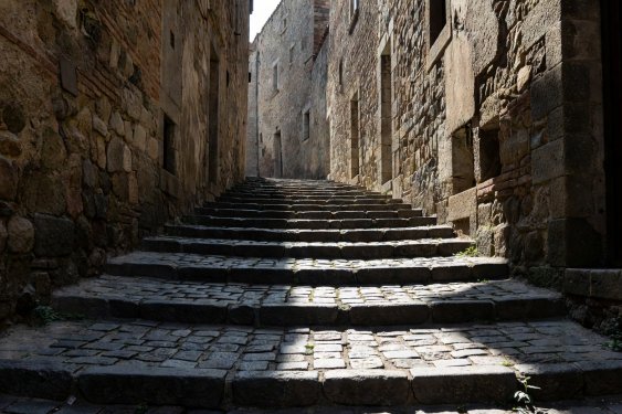 Steep narrow cobblestone steps flanked by historic masonry walls in high contrast daylight
